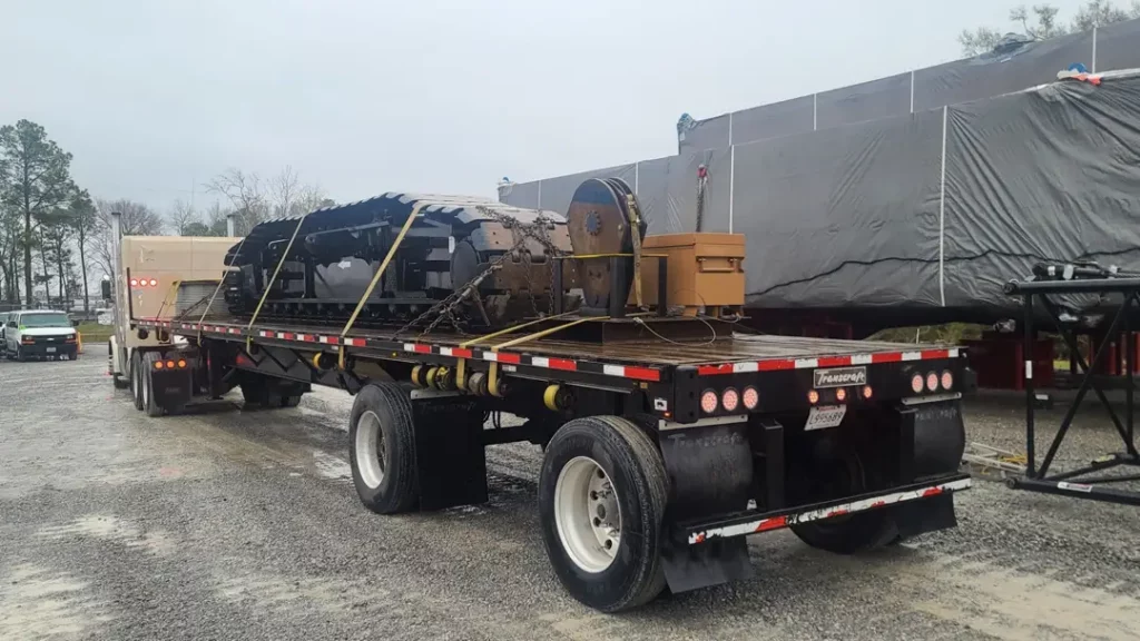 rear view of ferrara transport services flatbed hauling crane skid